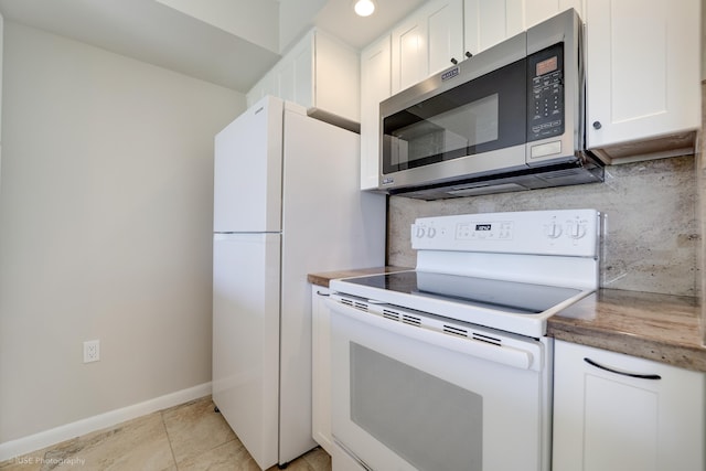 kitchen with white cabinetry, white appliances, light tile patterned flooring, and backsplash