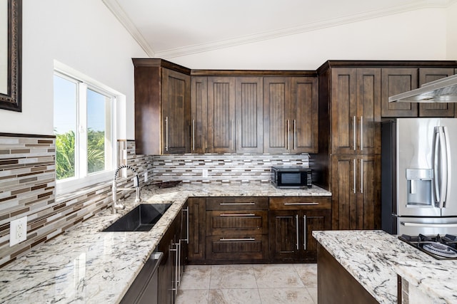 kitchen with light stone counters, dark brown cabinetry, sink, and stainless steel fridge with ice dispenser