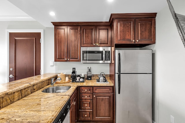 kitchen with light stone counters, crown molding, stainless steel appliances, a sink, and dark brown cabinets