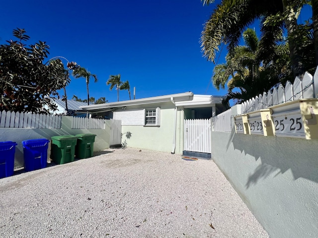 rear view of property with fence, a gate, and stucco siding