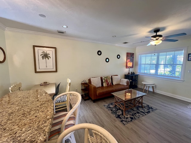 living area with ornamental molding, visible vents, baseboards, and wood finished floors