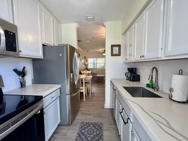 kitchen featuring white cabinetry, a sink, electric range, and light stone countertops