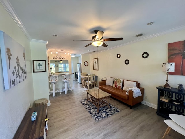 living area with ornamental molding, visible vents, and wood finished floors