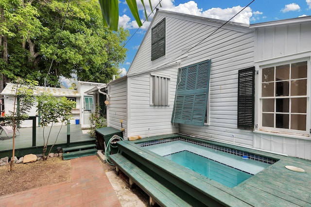 back of house with an in ground hot tub