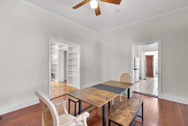 dining space featuring wood-type flooring, a ceiling fan, baseboards, and ornamental molding