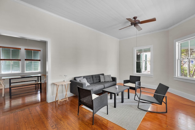 living room featuring ceiling fan, baseboards, crown molding, and wood finished floors