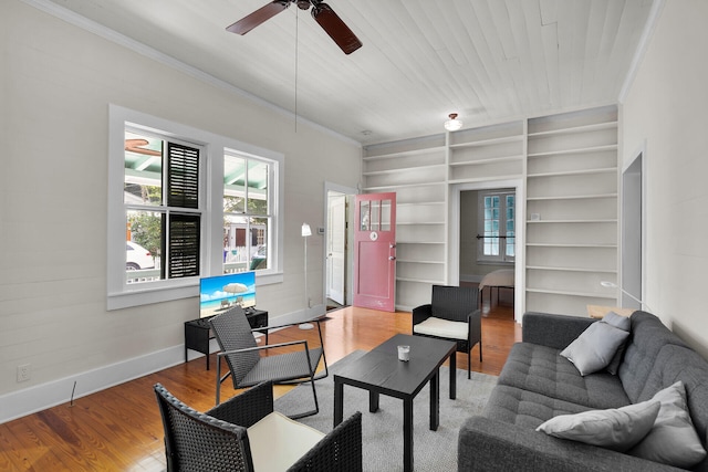 living area with baseboards, built in shelves, and ornamental molding