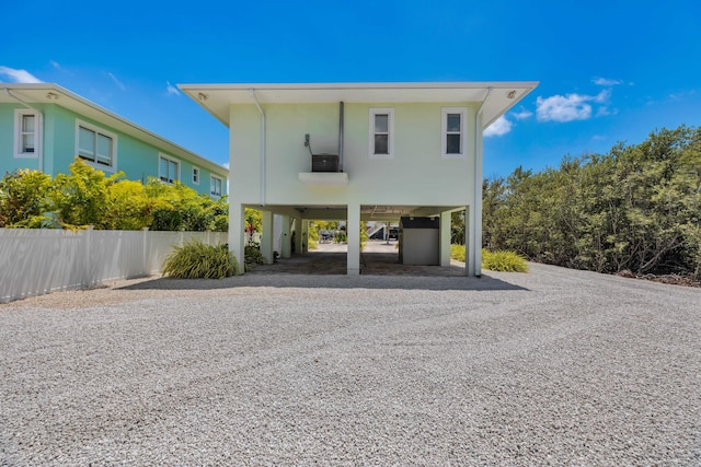 view of vehicle parking with a carport, fence, and gravel driveway