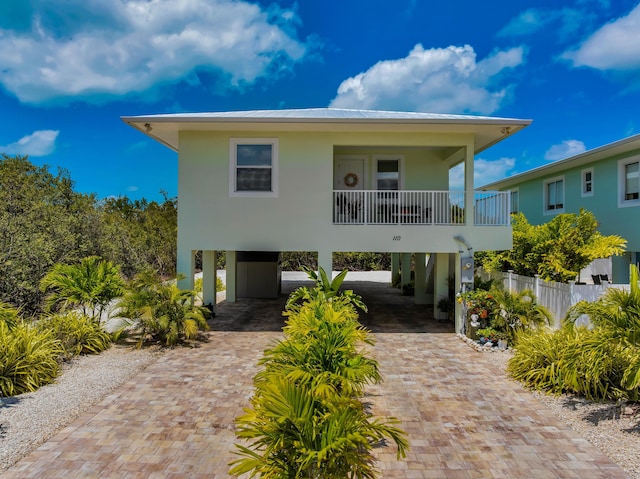 coastal inspired home featuring metal roof, fence, a carport, and decorative driveway