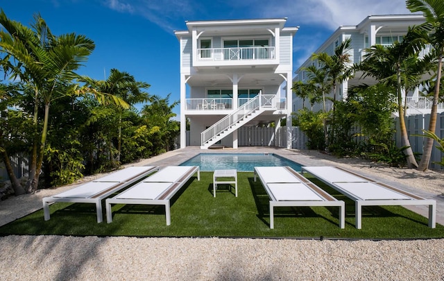 rear view of house featuring a fenced in pool, a lawn, a patio, and a balcony