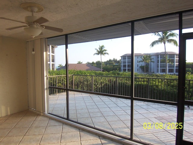 doorway to outside with tile patterned floors, a ceiling fan, and expansive windows