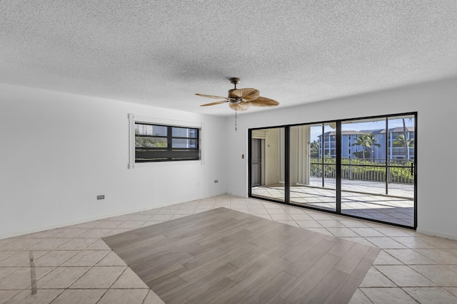 unfurnished room with light tile patterned floors, baseboards, a textured ceiling, and ceiling fan