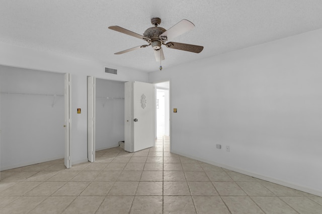 unfurnished bedroom featuring visible vents, baseboards, two closets, and a textured ceiling