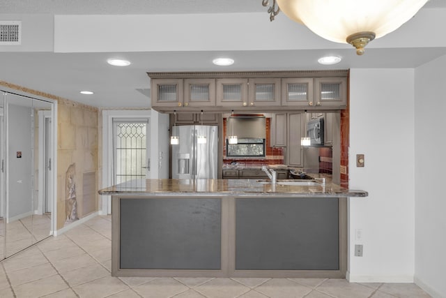 kitchen featuring visible vents, a sink, stainless steel appliances, a peninsula, and glass insert cabinets