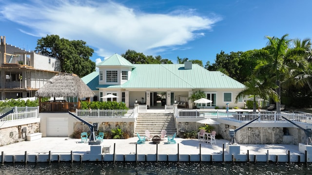 back of property with a pool, a patio, and a water view