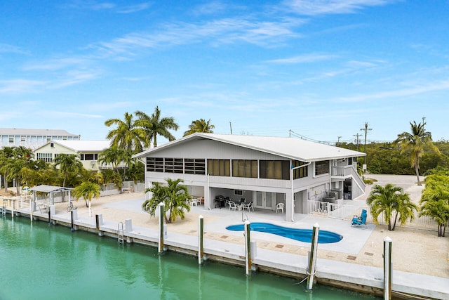 back of house featuring a water view, a sunroom, and a patio