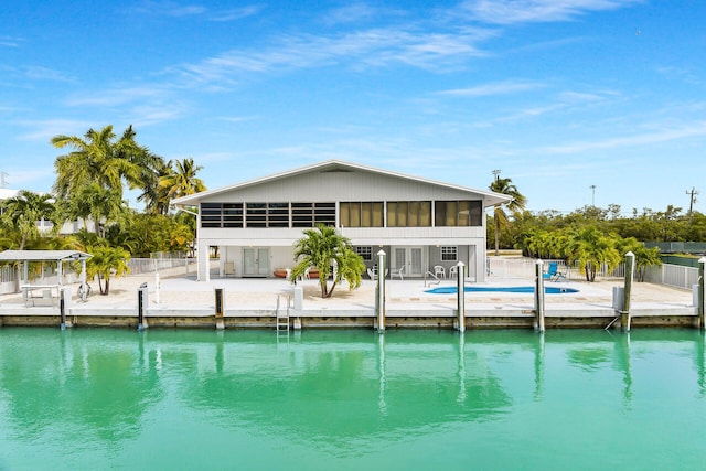 rear view of house with a community pool, a patio area, a sunroom, and a water view