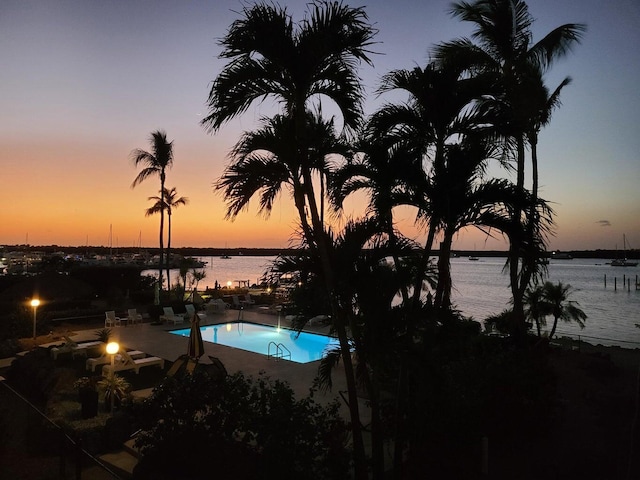 pool with a patio area, a fire pit, and a water view