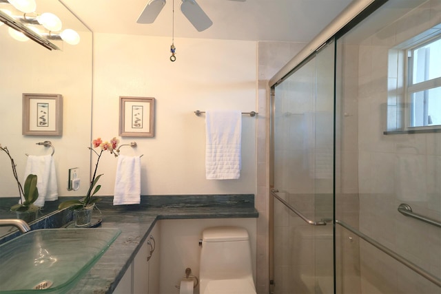 bathroom with vanity, toilet, a stall shower, and ceiling fan