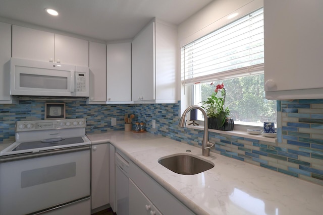 kitchen featuring light stone countertops, decorative backsplash, white appliances, white cabinetry, and a sink