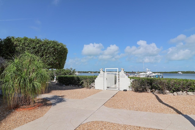 view of yard with a fenced front yard, a water view, and a gate