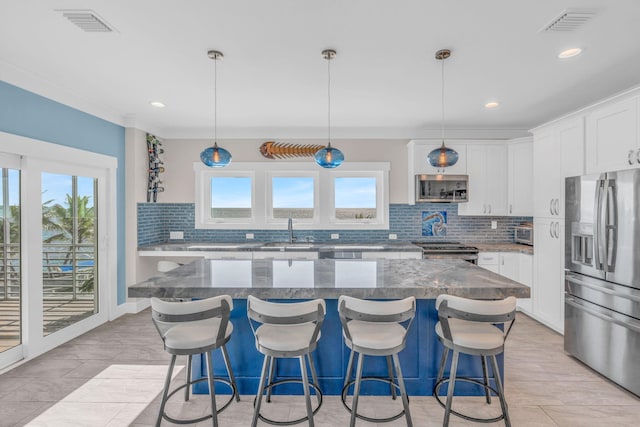 kitchen with white cabinetry, a center island, stone counters, pendant lighting, and stainless steel appliances