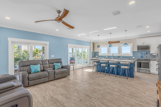 living room with crown molding, sink, and ceiling fan