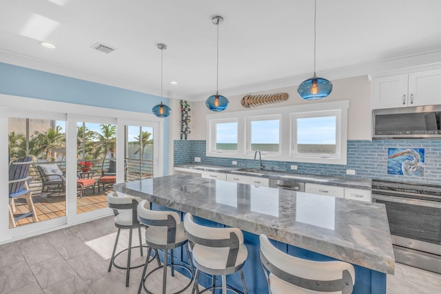 kitchen with decorative light fixtures, white cabinetry, dark stone counters, a center island, and stainless steel appliances