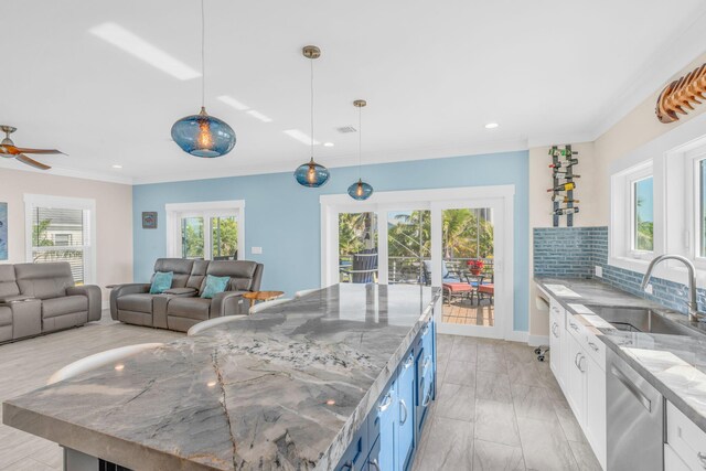 kitchen featuring tasteful backsplash, sink, white cabinets, hanging light fixtures, and light stone countertops