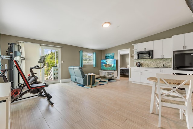 exercise room featuring lofted ceiling and light hardwood / wood-style floors