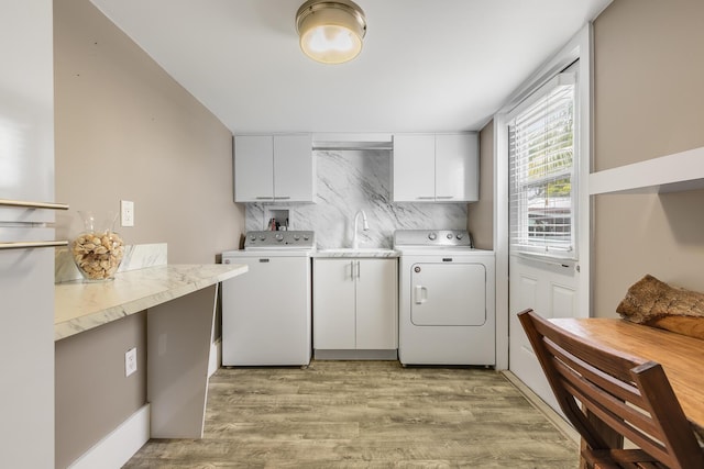 washroom with sink, washing machine and dryer, cabinets, and light wood-type flooring