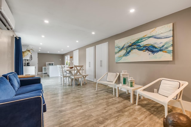 living room with a wall unit AC and light hardwood / wood-style flooring