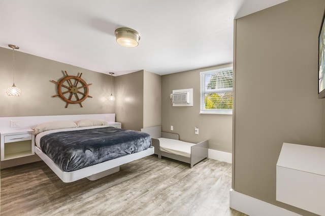 bedroom featuring hardwood / wood-style floors and a wall unit AC