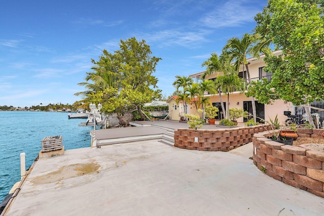 view of patio / terrace with a boat dock, a balcony, and a water view