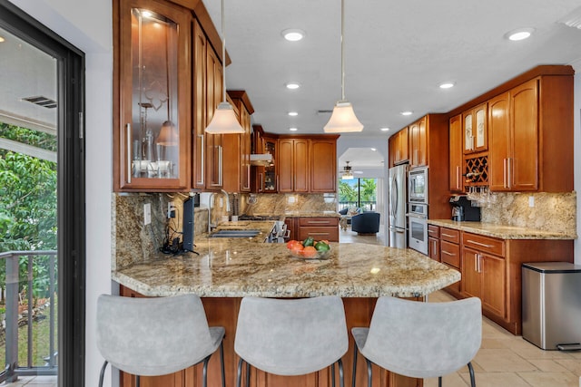 kitchen featuring sink, a breakfast bar area, kitchen peninsula, pendant lighting, and stainless steel appliances