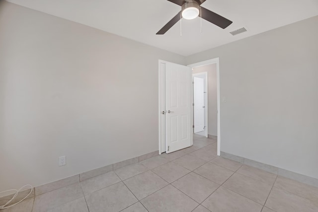 empty room featuring a ceiling fan, baseboards, visible vents, and light tile patterned flooring