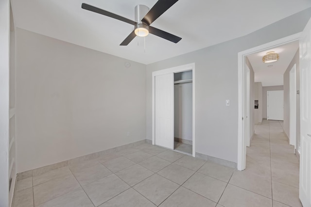 unfurnished bedroom featuring ceiling fan, a closet, and light tile patterned floors