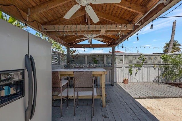 wooden terrace with a sink, ceiling fan, a gazebo, and outdoor dry bar
