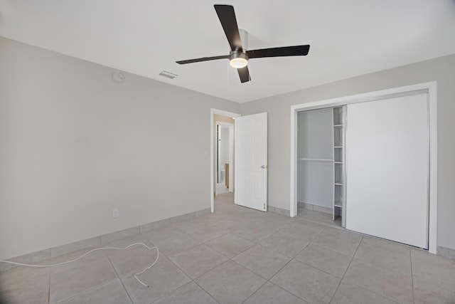 unfurnished bedroom featuring light tile patterned floors, a closet, visible vents, baseboards, and ceiling fan