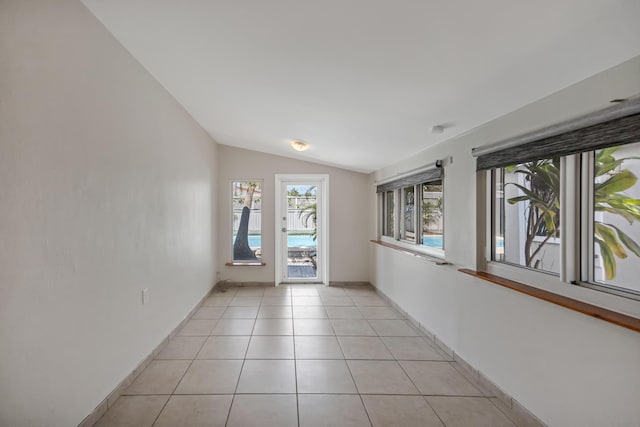 unfurnished room with light tile patterned floors, vaulted ceiling, and baseboards