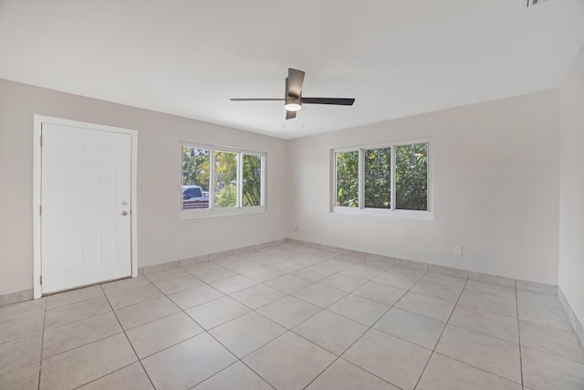 empty room with light tile patterned flooring and a ceiling fan