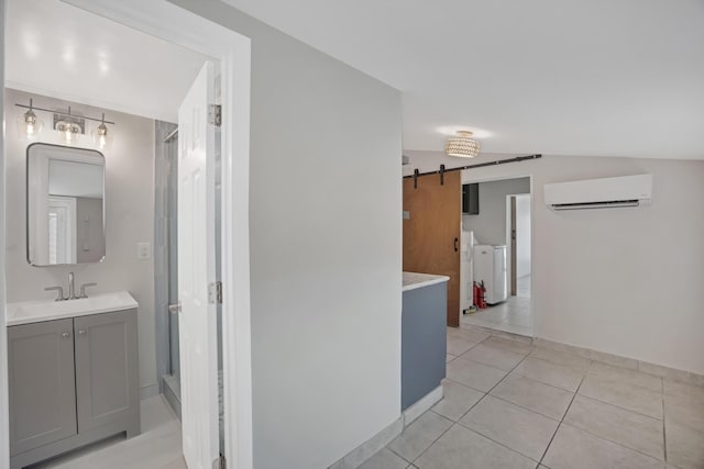 hall featuring light tile patterned floors, a sink, separate washer and dryer, a wall mounted air conditioner, and a barn door