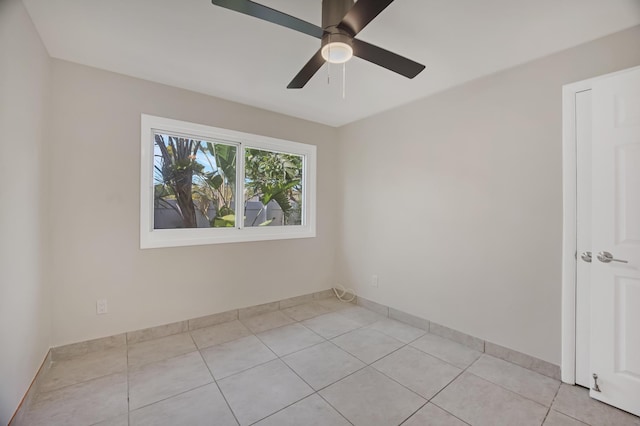 unfurnished room with ceiling fan, baseboards, and light tile patterned floors