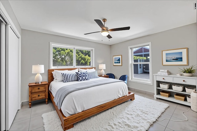 bedroom with multiple windows, a ceiling fan, a closet, and light tile patterned flooring