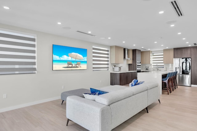 living room with light wood-style floors, baseboards, recessed lighting, and visible vents