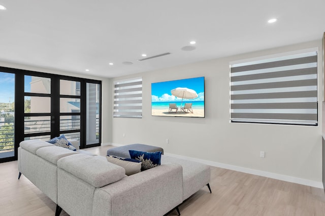 living room with light hardwood / wood-style flooring, french doors, and a wall of windows