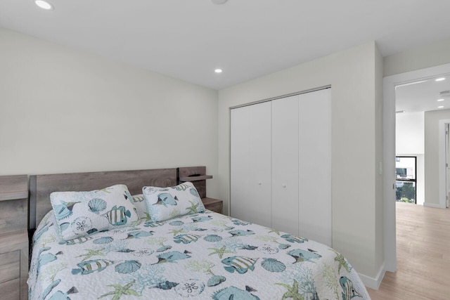 bedroom featuring recessed lighting, baseboards, light wood finished floors, and a closet