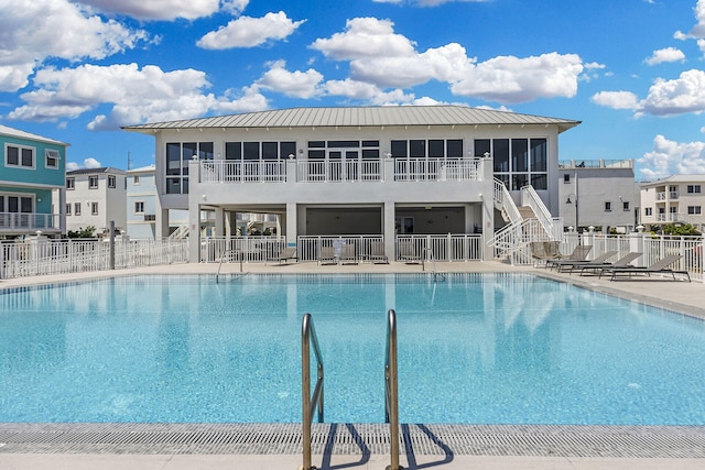 pool with fence, stairs, a sunroom, and a patio