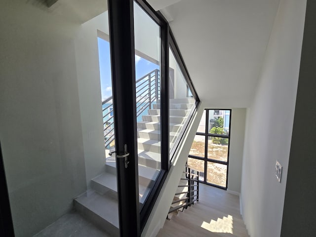 stairs with baseboards, expansive windows, and wood finished floors