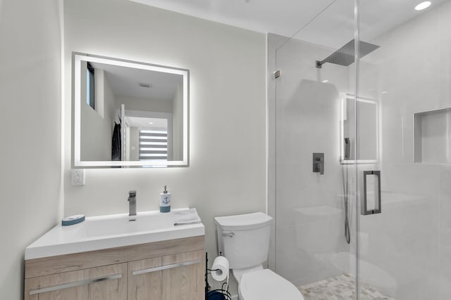 bathroom with walk in shower, vanity, and toilet